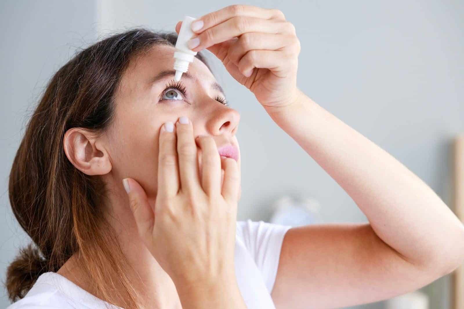 Frau gibt sich Augentropfen gegen trockene Augen ins Auge